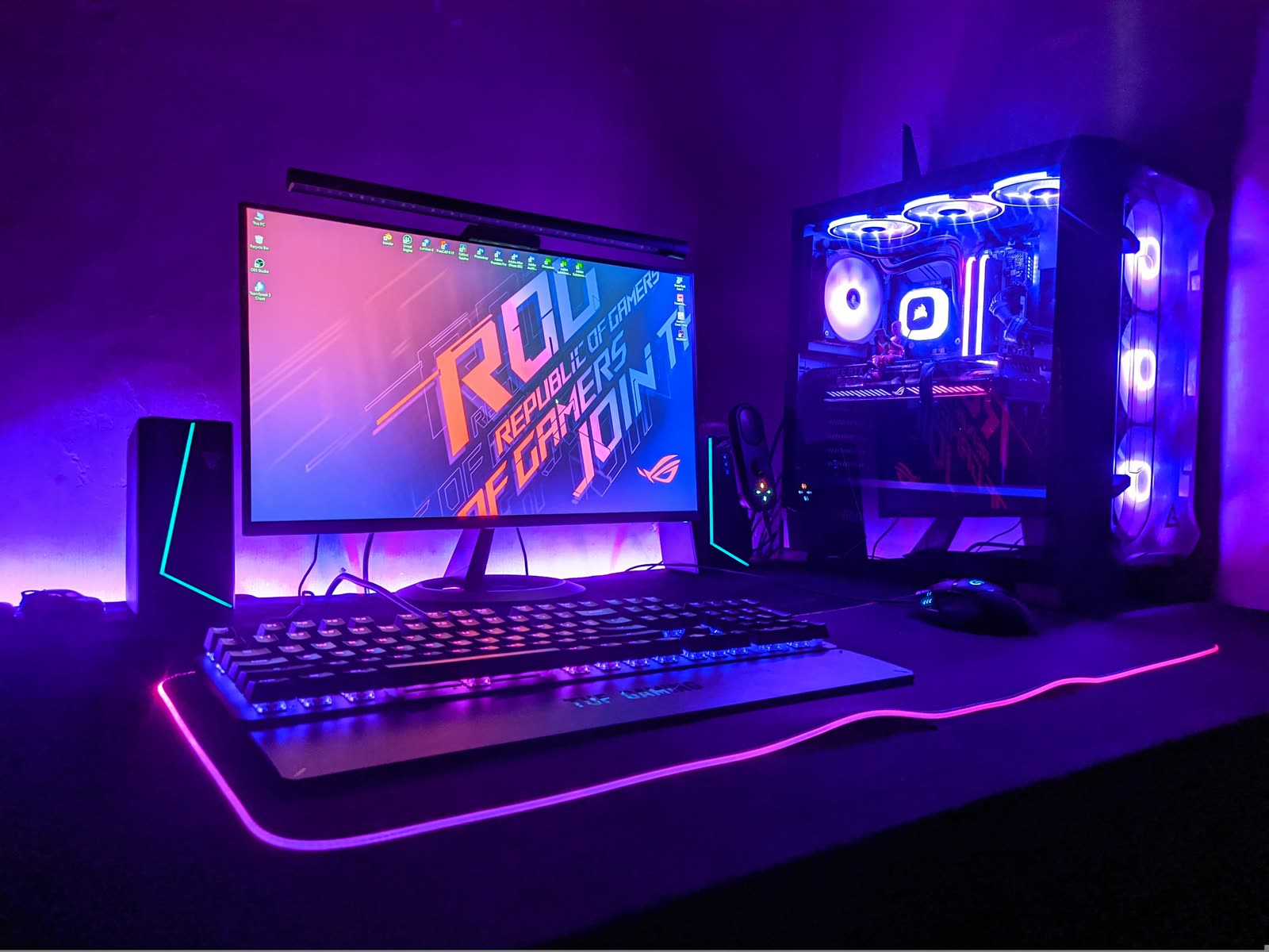 Un poste de jeu éclairé en violet : écran, clavier lumineux et tour vitrée